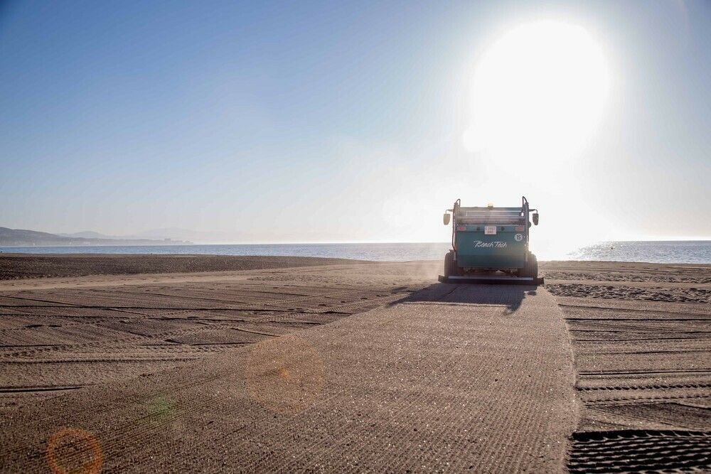 Citazione con foto di pulitore da spiaggia semovente e spiaggia sullo sfondo