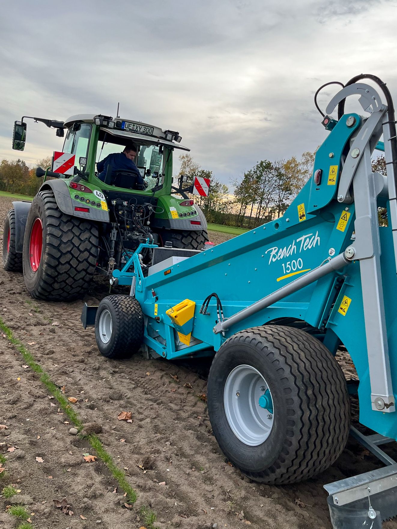 Traktor mit angebauter BeachTech 1500 Maschine bei der Bodenbearbeitung auf einem Feld.