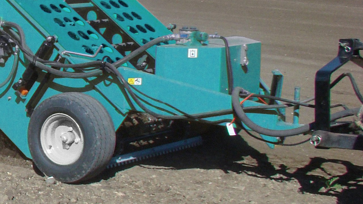BeachTech Maschine nimmt mit höhenverstellbarem Schar die oberste Bodenschicht auf und transportiert Erde und Steine ins Innere