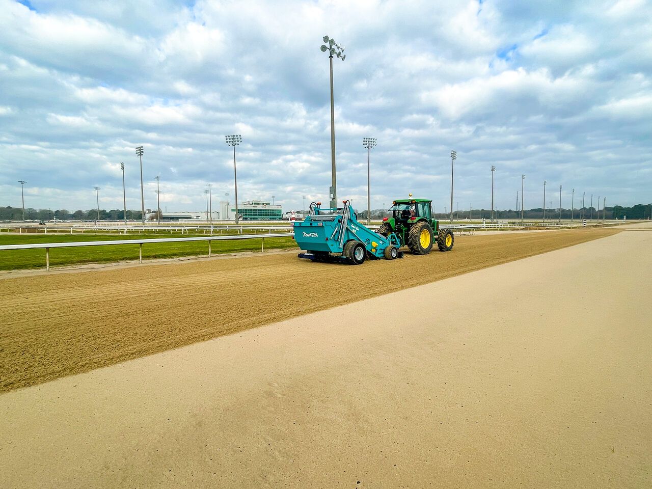 Traktor mit BeachTech Maschine reinigt und glättet die Sandfläche einer Reitanlage.