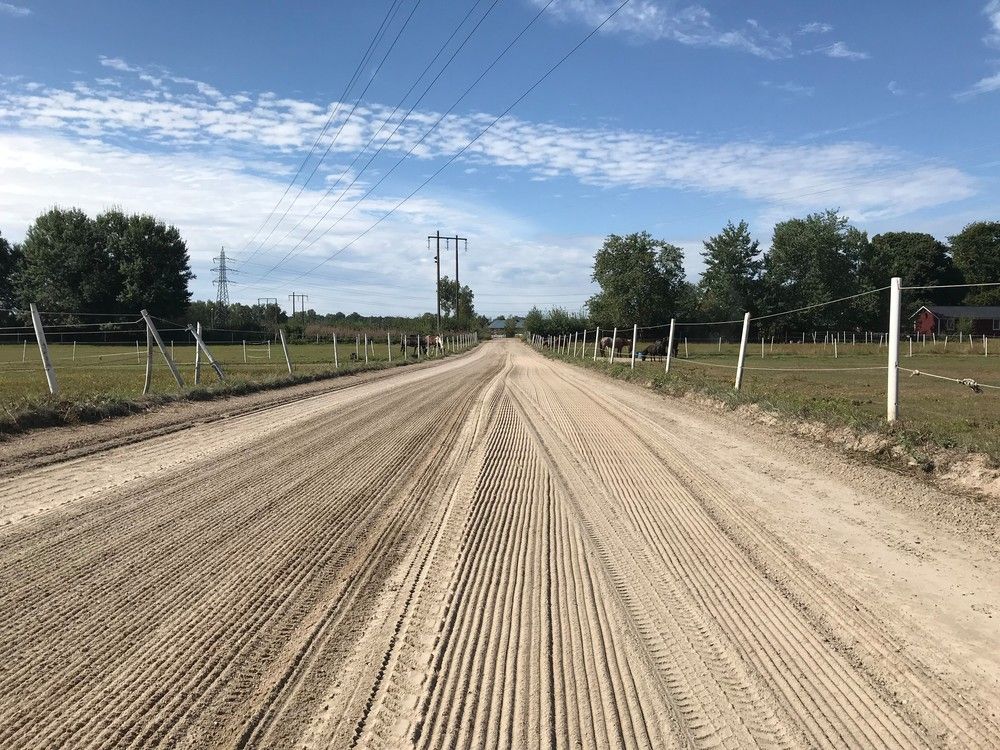 Gereinigte und geglättete Sandfläche auf einer langen Anlage mit Zaun und Stromleitungen im Hintergrund.