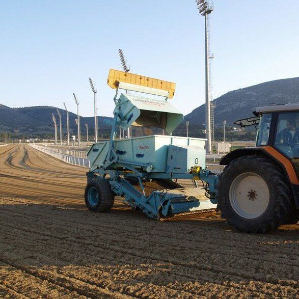 Traktor mit BeachTech Maschine bei der Reinigung und Pflege einer Reitsportanlage, um den Sandboden gleichmäßig und sicher für Pferde zu halten.