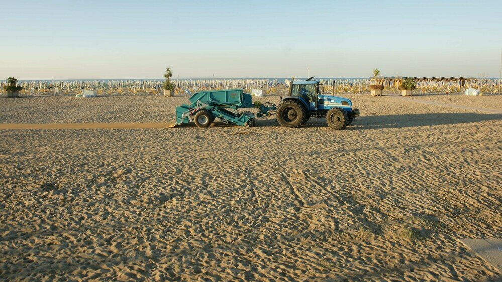Gezogener Strandreiniger mit Traktor am Strand