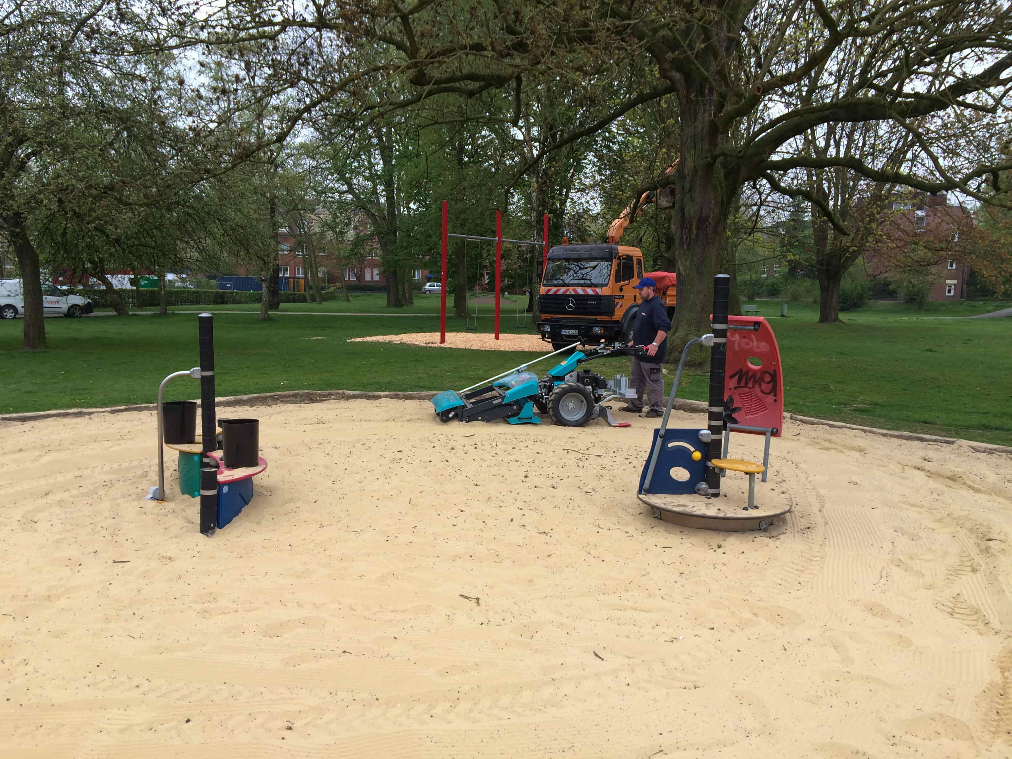 Handgeführter BeachTech Reiniger säubert den Sand eines Spielplatzes, um die Fläche für Kinder hygienisch und sicher zu halten.
