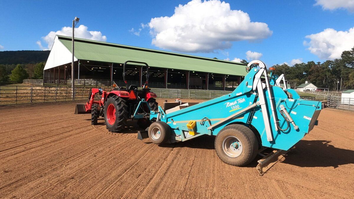 Traktor mit BeachTech Maschine bei der Reinigung und Glättung einer Reitplatzfläche.